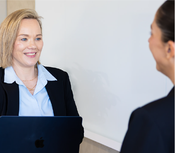Female with blond hair and blue shirt talking to woman with dark hair