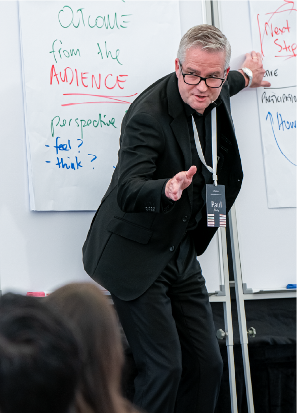 Male standing at two flipcharts speaking to audience